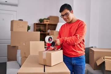 Wall Mural - Down syndrome man smiling confident packing cardboard box at new home