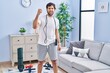 © Krakenimages.com - Handsome latin man wearing sportswear at home angry and mad raising fist frustrated and furious while shouting with anger. rage and aggressive concept.