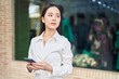 © Krakenimages.com - Young chinese woman using smartphone with serious expression at street