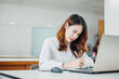 © nateejindakum - Stylish and beautiful girl working analytics with computer laptop. Positive businesswoman is writting some notes.