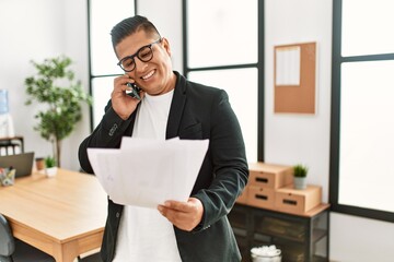 Sticker - Young latin businessman talking on the smartphone working at the office.