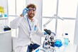 © Krakenimages.com - Young hispanic man wearing scientist uniform using microscope at laboratory