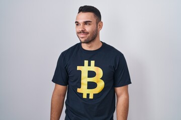 Sticker - Young hispanic man wearing bitcoin t shirt smiling looking to the side and staring away thinking.