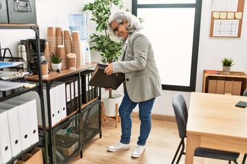 Canvas Print - Middle age grey-haired businesswoman smiling happy working at the office.