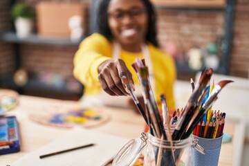 Poster - African american woman artist smiling confident holding paintbrush at art studio