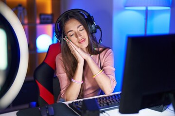 Poster - Young hispanic woman playing video games sleeping tired dreaming and posing with hands together while smiling with closed eyes.