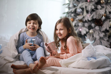 Wall Mural - A family with children having fun on the bed under the covers during the Christmas holidays.