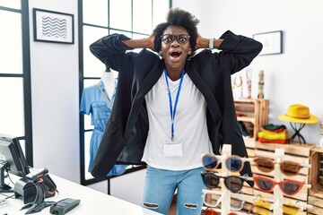 Canvas Print - African young woman working as manager at retail boutique crazy and scared with hands on head, afraid and surprised of shock with open mouth