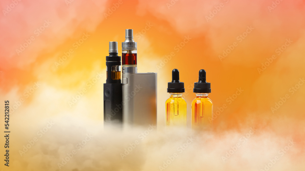Steam smoking. Vape pens. Oil bottles for refilling electronic cigarettes.  Oils for vaping oil for refilling vape pens. Vape cigarettes on orange.  Vaping kit in smoke. Sale gadgets for vapers concept Stock