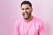 © Krakenimages.com - Hispanic young man standing over pink background angry and mad screaming frustrated and furious, shouting with anger. rage and aggressive concept.