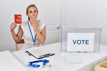 Wall Mural - Young blonde woman at political campaign election holding swiss passport covering mouth with hand, shocked and afraid for mistake. surprised expression