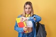 © Krakenimages.com - Young blonde woman wearing student backpack and holding books looking at the watch time worried, afraid of getting late