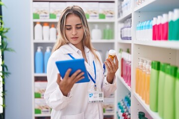 Sticker - Young blonde woman pharmacist using touchpad holding pills bottle at pharmacy