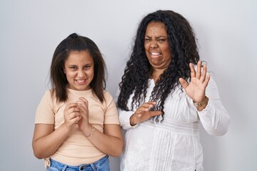 Sticker - Mother and young daughter standing over white background disgusted expression, displeased and fearful doing disgust face because aversion reaction.