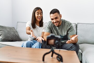 Young latin couple having video call sitting on the sofa at living room.