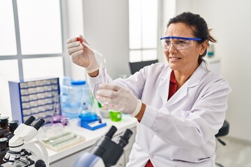 Sticker - Middle age hispanic woman wearing scientist uniform using pipette at laboratory