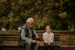 © BGStock72 - Grandfather spending time with his granddaughter on bench in park on autumn day