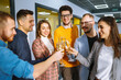 © maxbelchenko - Group of young business people toasting each other and smiling while standing in the office.Partners celebrating their victory. Birthday, new year, christmas concept.