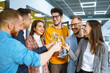 © maxbelchenko - Group of young business people toasting each other and smiling while standing in the office.Partners celebrating their victory. Birthday, new year, christmas concept.