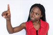 Interested woman touching virtual screen. Female African American model in red vest scrolling virtual screen, pressing bottoms. Portrait, studio shot, technology concept
