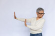 Portrait of senior woman making stop gesture in disgust. Mature Caucasian woman wearing eyeglasses and white jumper refusing to look at something. Refusal and denial concept