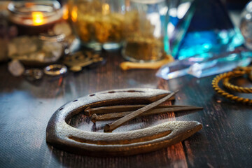 Wall Mural - A very soft focus on traditional iron products. An old horseshoe and hand-forged antique nails from the 19th century. Concept of blurred mystical background with candles and potions on a wooden table.