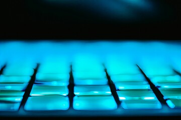 AI generated illustration of the computer keyboard with neon blue light, close-up