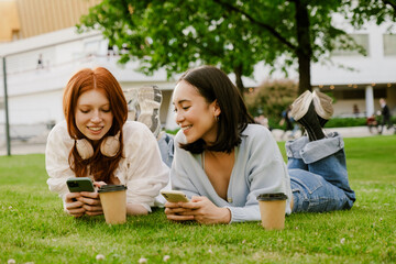 Wall Mural - Young multinational women drinking coffee and using cellphone