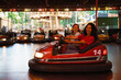 © Drobot Dean - Young beautiful enthusiastic girls riding bump car in amusement park