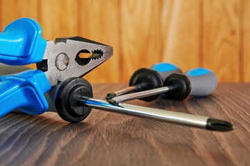 Worker equip, screwdriver and pliers on the wooden table in workshop. Instruments and tools backgrounds