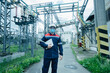 © Andrii - A masked power engineer during a pandemic inspects the modern equipment of an electrical substation before commissioning. Energy and industry. Scheduled repair of electrical equipment.