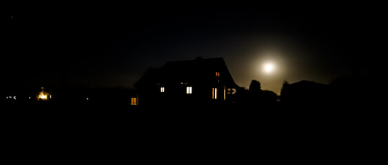 Wooden country house with light in the windows during a moonlit night