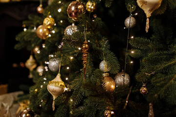 Wall Mural - Close up view of beautiful fir branches with shiny golden bauble or ball, xmas ornaments and lights, Christmas holidays background. copy space. Decoration on christmas tree. Festive new 2023 year