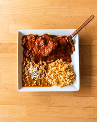 Wall Mural - Top view of Charro beans and rice with a side of Mole on a wooden surface