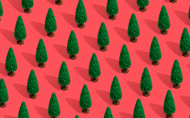 Wall Mural - Minimal composition pattern background of green Christmas trees on pastel red. New Year concept.