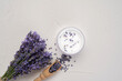 Bunch of fresh lavender flowers and moisturizing face cream on white background. Top view, flat lay mock up, copy space. Natural herbal cosmetics. Minimal background