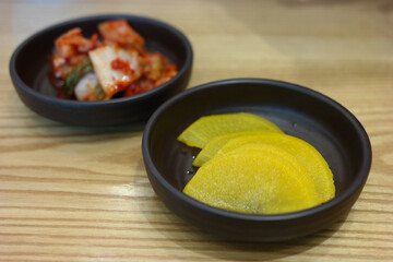 Wall Mural - Pickled radish and kimchi are served as side dishes on a round plate.