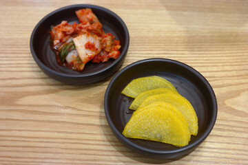 Wall Mural - Pickled radish and kimchi are served as side dishes on a round plate.