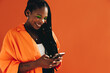 © Jacob Lund - Smiling black woman sending a text message on her smartphone in a studio