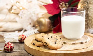 Wall Mural - Christmas cookies and glass of milk for Santa on holiday blurred background.