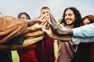 joyful group of multi-ethnic community of happy people having fun joining hands in the park - multie