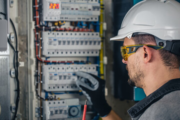 Wall Mural - Man, an electrical technician working in a switchboard with fuses.