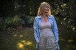 © Westend61 - Smiling mature woman standing with hands in pockets at garden