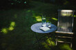 © Westend61 - Open book and glass of water on table with chair in garden
