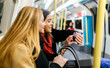 © Westend61 - UK, London, Two young women in the underground looking at smart watch