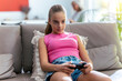 © Westend61 - Concentrated girl playing video game with joystick sitting on sofa at home