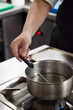 © Moha - Chef hand using thermometer on boiling water vertical stills.