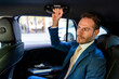 © Westend61 - Businessman holding handle sitting in taxi