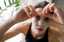 Woman Peeling Off Face Mask At Home