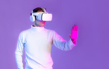 Wall Mural - Metaverse, asian man in white t shirt wearing vr goggles headset and headphone hand touching on purple color background.
